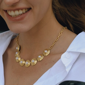 Elegant gold clover necklace with pearls on a model wearing a white shirt