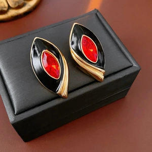 Vintage gold-trimmed oval stud earrings with black enamel and red crystal centers
