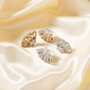 Elegant wing-shaped stud earrings with sparkling cubic zirconia on champagne silk background