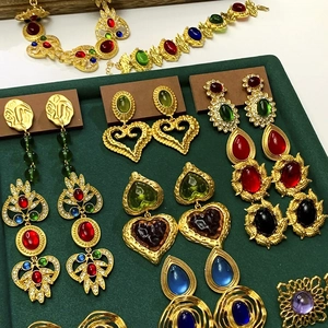 Dettaglio di orecchini e collane d'oro vintage con pietre preziose colorate su vassoio