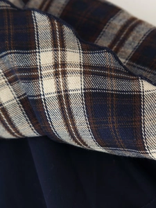 Detailed close-up of plaid fabric texture and wavy edge embroidery on the strap top