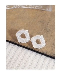 Macro shot of silver lava texture earrings with milky white agate round inlay detail
