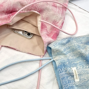 Detail of tie-dye lace tote bag with internal storage pocket and leather shoulder strap