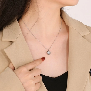 Close-up of elegant round rhinestone pendant on a silver snake chain over casual wear