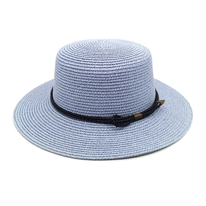 Close-up of a light blue straw sun hat featuring a black leather woven trim and metal charm