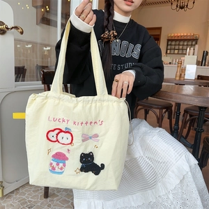 Close-up of cute cat embroidery and drawstring detail on yellow canvas tote bag