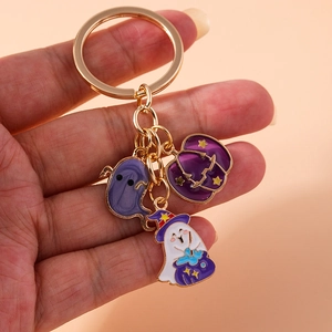 Detail of Halloween keychain with purple ghost and pumpkin enamel charms on gold ring