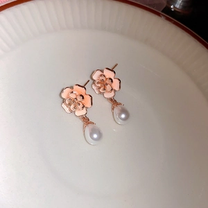 Dettaglio ravvicinato di orecchini a fiore rosa con pendenti di perle su piatto in ceramica