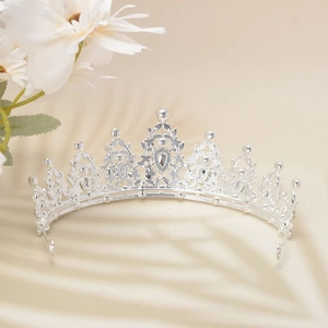 Detailed view of silver Baroque crown with sparkling rhinestones on beige background