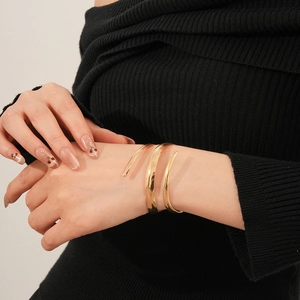 Bracciale rigido a spirale dorato a tre strati su modella con maglione nero