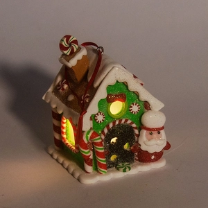 Close-up of lighted Christmas gingerbread house with snowy roof and Santa figurine