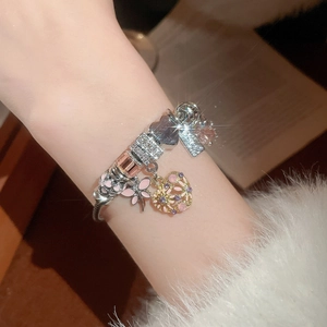Detail of silver-plated heart charm bracelet with pink butterfly and zircon beads