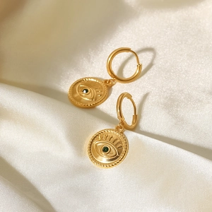 Macro detail of 18K gold plated evil eye drop earrings with green gemstone on silk