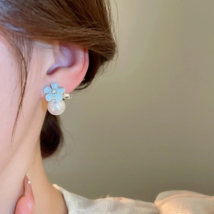 Close-up of model wearing elegant light blue flower earrings with pearls and crystals