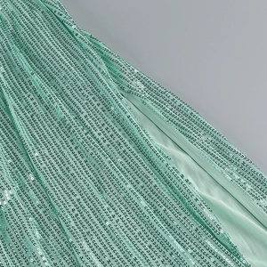 Detail of light mint green sequins sewn on mesh fabric with elegant pleated texture