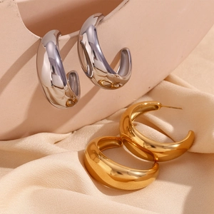 Detail of chunky gold and silver C-shaped hoop earrings with polished mirror finish