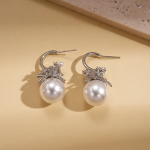 Detail view of elegant C-shaped silver pearl earrings with ribbon metal texture