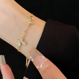 Detail of gold plated butterfly bracelet with white mother of pearl and zircon stones