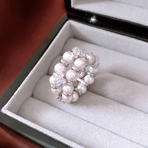 Double-layered pink pearl ring with silver flower details in a gray jewelry box