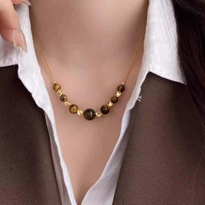 Elegant close-up of a Maillard style brown tiger eye beaded necklace worn by a female model