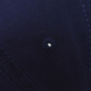 Close-up of navy blue twill cotton fabric with detailed embroidery eyelet and stitching
