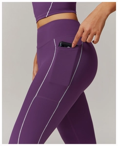 Detalle de leggings de yoga morados de cintura alta con bolsillo lateral y costuras blancas