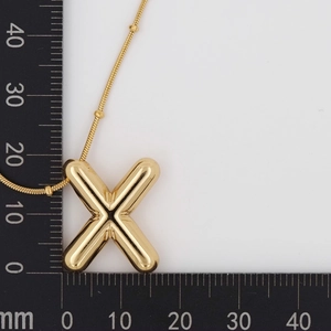 Macro shot of polished gold letter X pendant with size measurements on 20mm scale