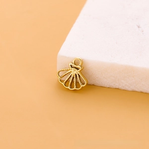 Gros plan d'un pendentif coquillage en acier inoxydable doré avec texture en relief et anneau