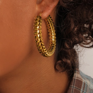 Detail of chunky gold chunky braided hollow hoop earrings showing metallic woven texture