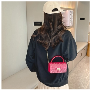 Model wearing a rose red mini jelly crossbody bag with pearl handle and chain strap