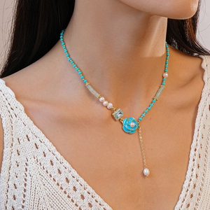 Detail of blue beaded necklace featuring a rose enamel pendant and crystal charm