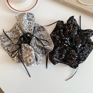 Detailed view of paisley print bow hair claw with pearl accents and heart-shaped clip