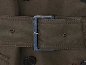Close-up of olive green trench coat belt with twill fabric and metal buckle detail