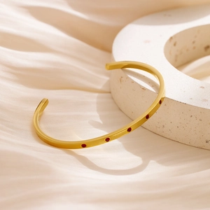 Detail of 18k gold plated stainless steel cuff bracelet with five red inlaid stones