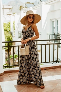 Detail of floral V-neck sleeveless maxi dress with a sun hat on a sunny terrace