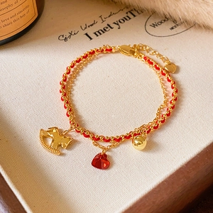 Dettaglio del bracciale a doppio strato in corda rossa con ciondoli a forma di cuore