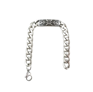 Close-up of silver metal chain bracelet featuring a rectangular star-engraved plate