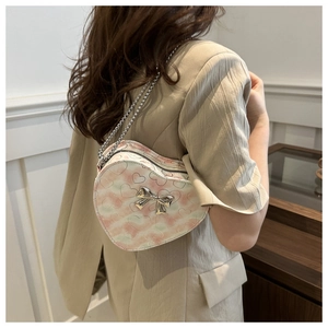 Detail view of pink tie-dye heart crossbody bag with silver bow and chain strap