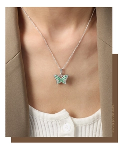 Détail d'un collier pendentif papillon argenté sur un mannequin en blazer marron
