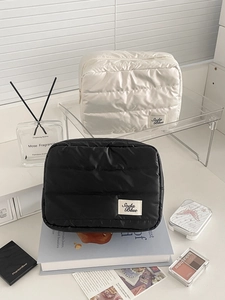 Detailed close-up of quilted waterproof nylon makeup bags in cream and black tones