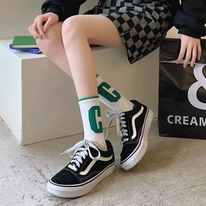 White crew sport socks with green letter C jacquard pattern worn in street style