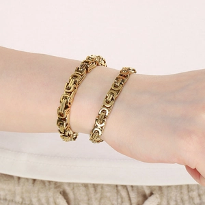 Detail showing two gold Byzantine chain bracelets in different thicknesses worn on a wrist