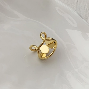 Close-up of golden adjustable ring with three round minimalist elements on white ceramic