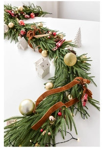 Detail of Norfolk pine garland with red gold baubles, velvet ribbon and LED lights