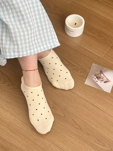 Gros plan de chaussettes invisibles à pois jaunes avec un bracelet de cheville rouge