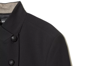 Detail of black blazer shoulder featuring embossed metal buttons and woven texture
