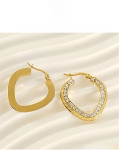 Detailed close-up of asymmetric gold plated heart hoop earrings with white crystals