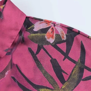 Dettaglio della stampa floreale tropicale su tessuto rosa con cuciture sulle spalle