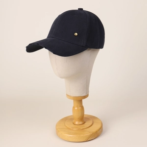 Distressed navy cotton baseball cap with vintage gold metal badge and curved brim