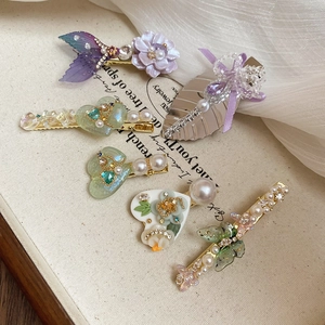 Détail de 6 barrettes à fleurs et feuilles avec perles et strass sur toile beige